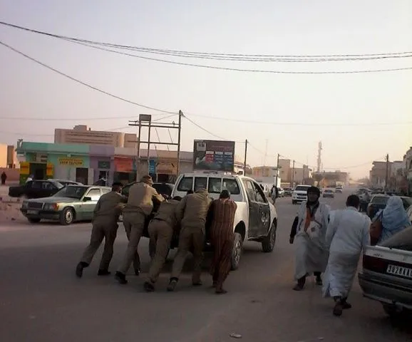 أفراد من الشرطة وهم يدفعون سيارتهم بأيديهم بعيد تفريق وقفة احتجاجية